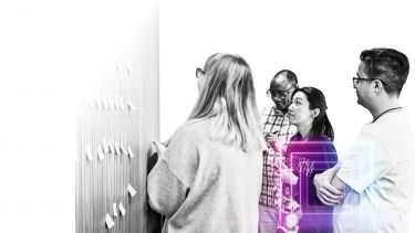 group of people looking at wall with post it notes